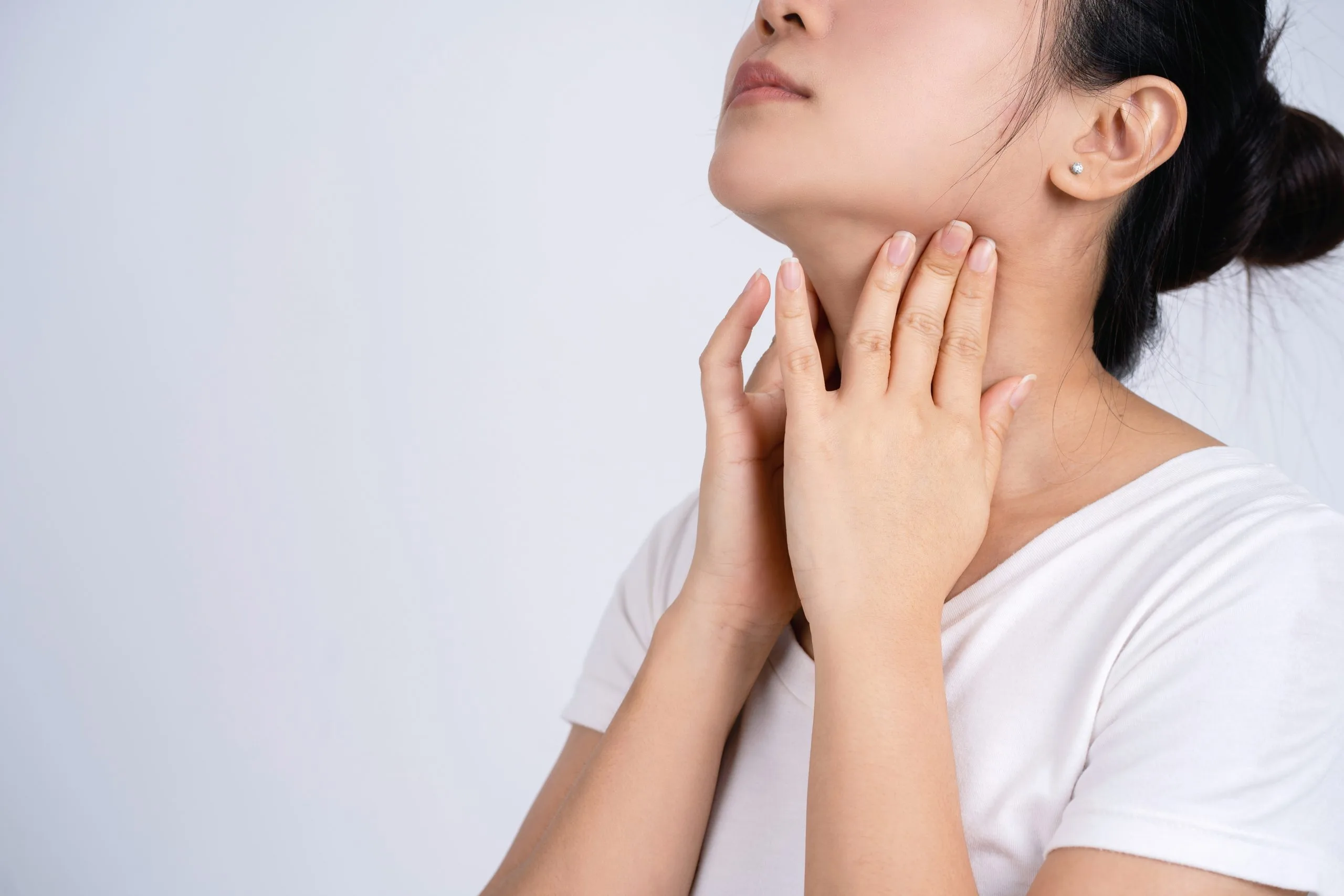 Woman touching her neck with both hands, illustrating thyroid problem symptoms