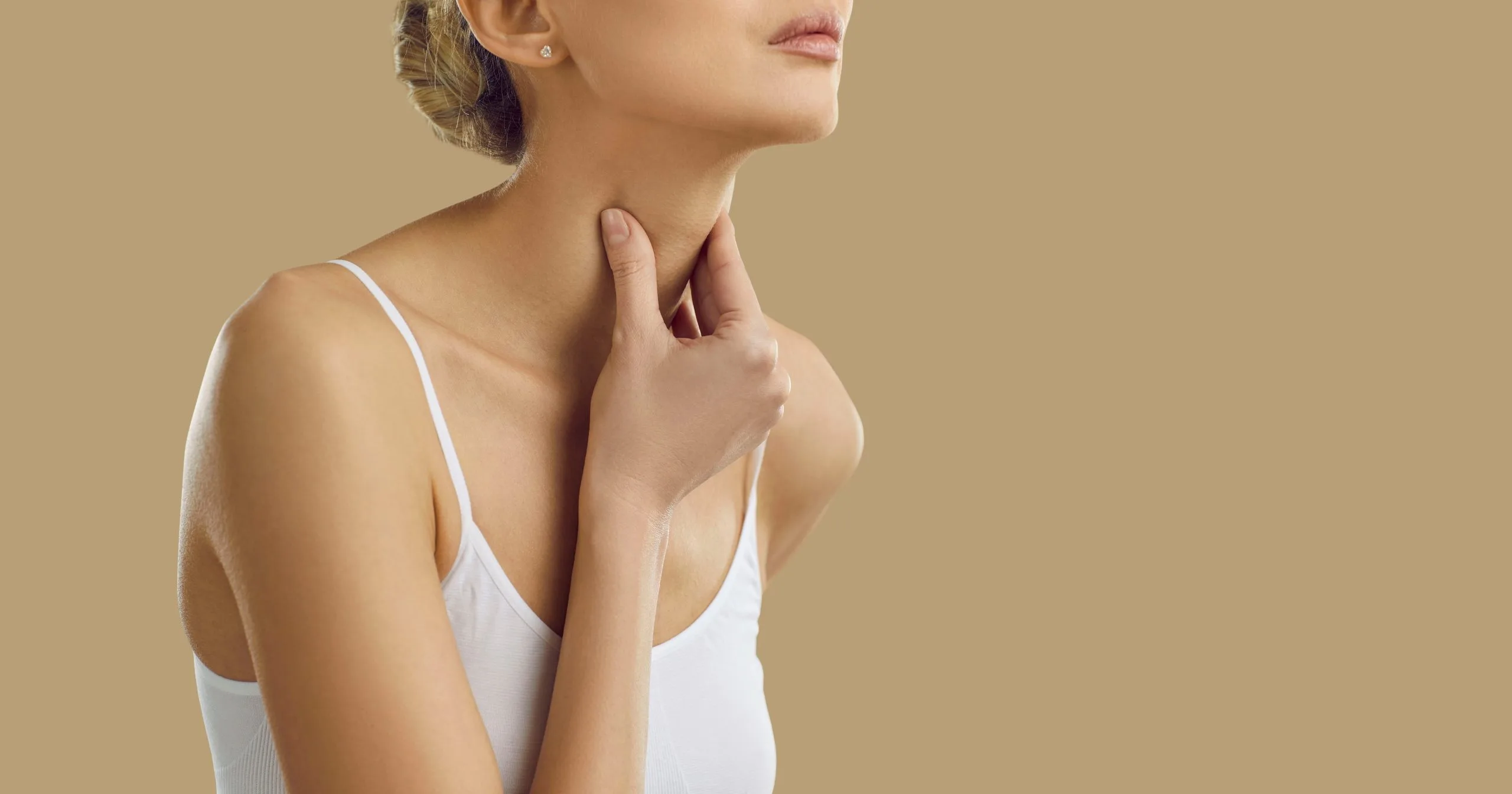 Woman touching her neck area in front of neutral background