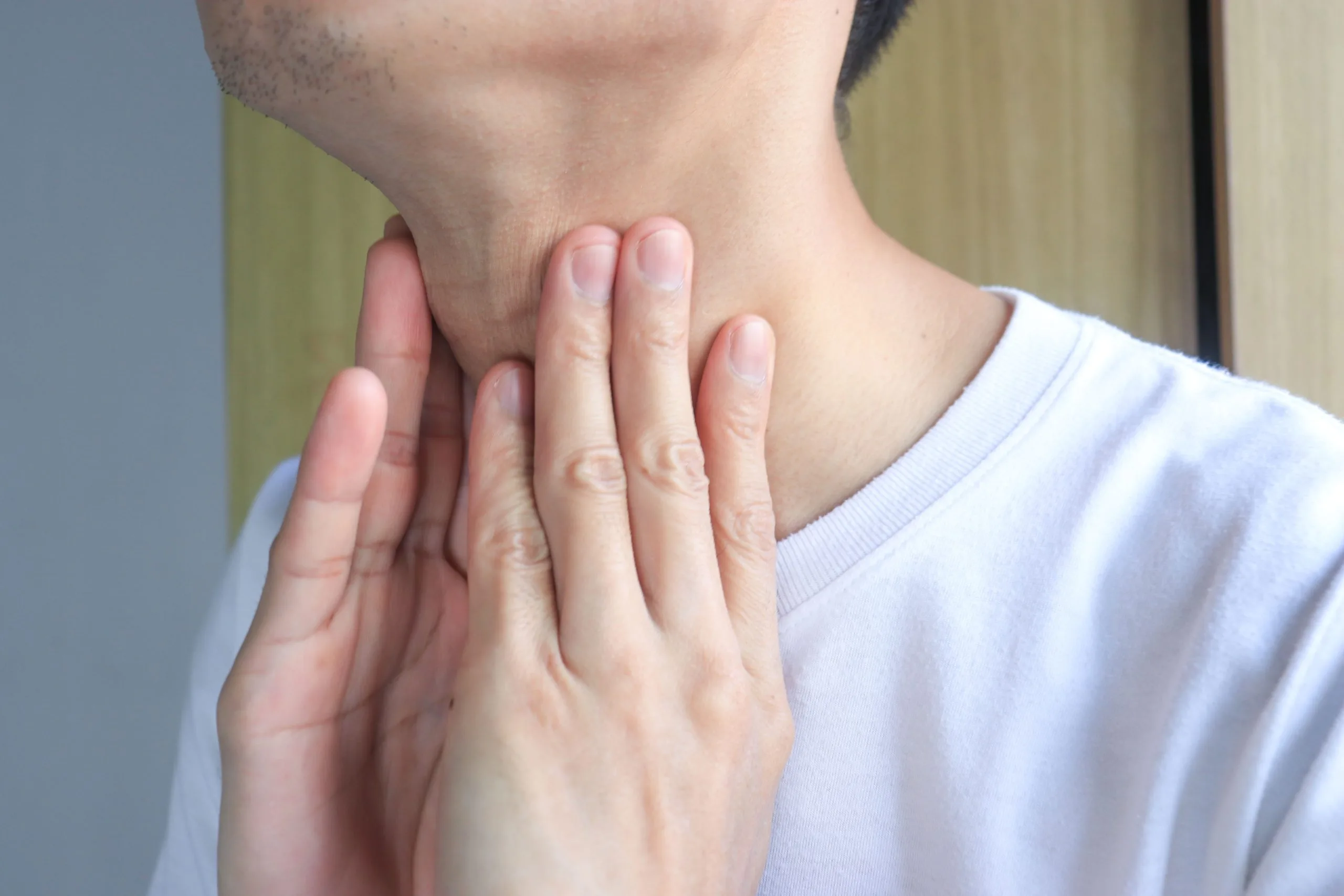 Man holding his throat with both hands, experiencing neck pain