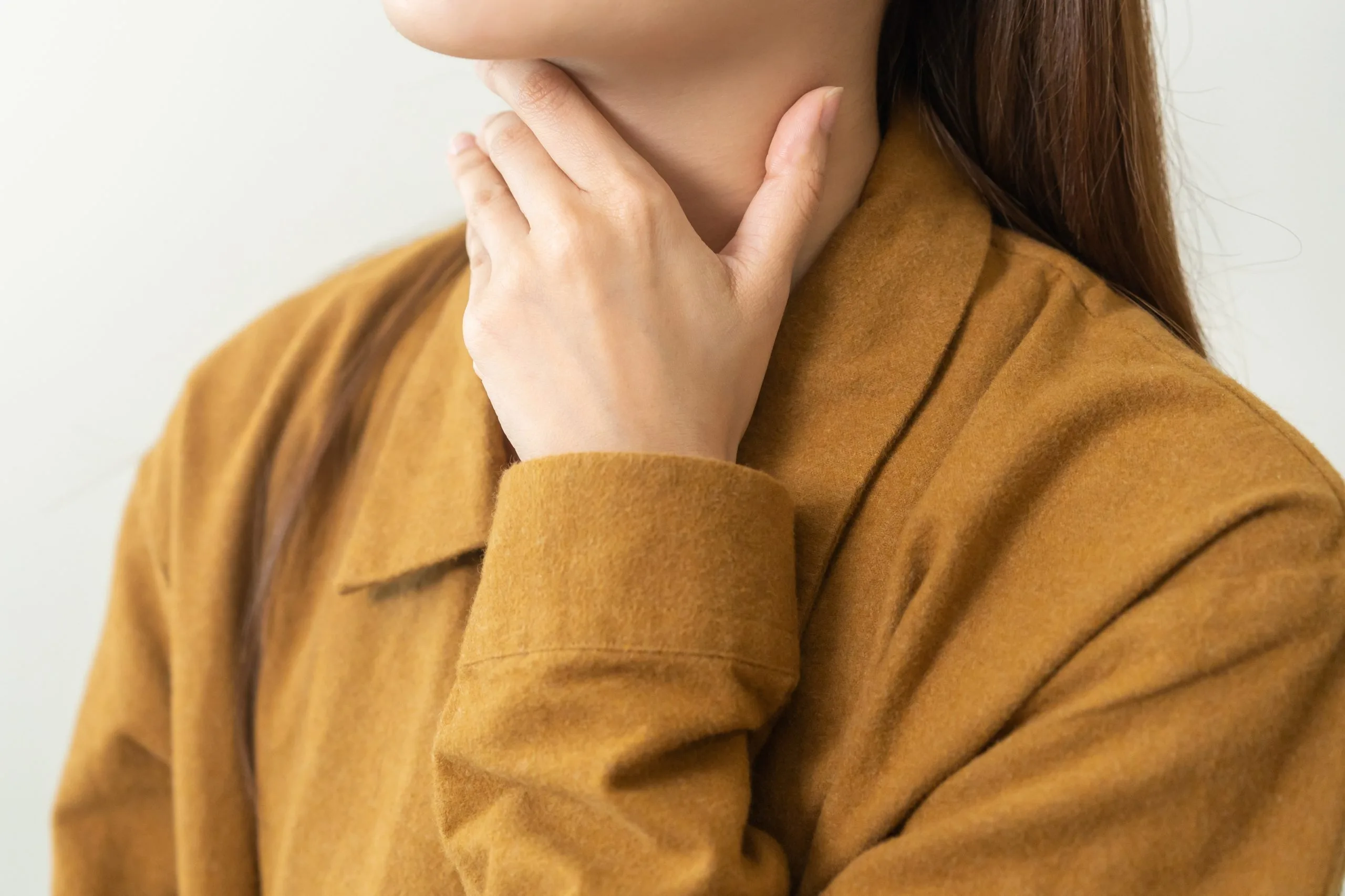 Woman touching her neck with both hands, showing thyroid area discomfort