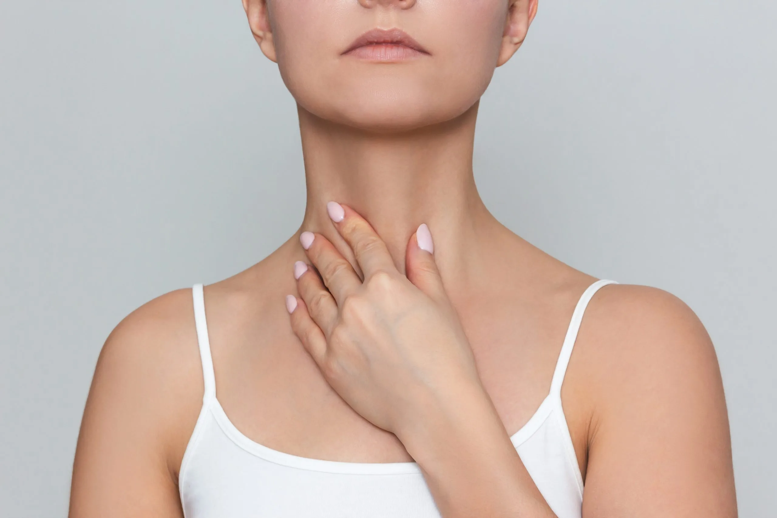 Woman touching her neck and thyroid area with her hand