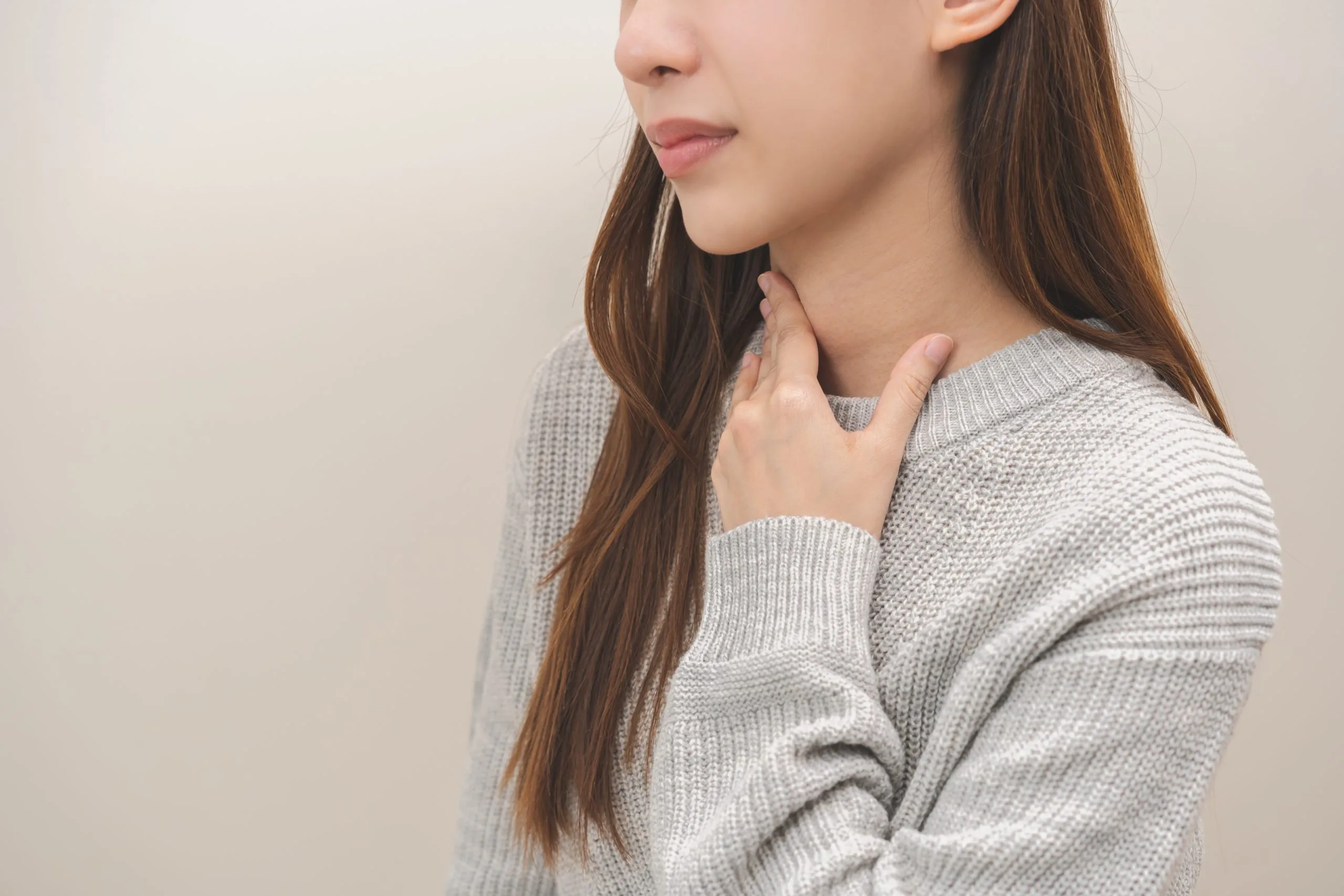 Woman touching her neck and throat area with both hands