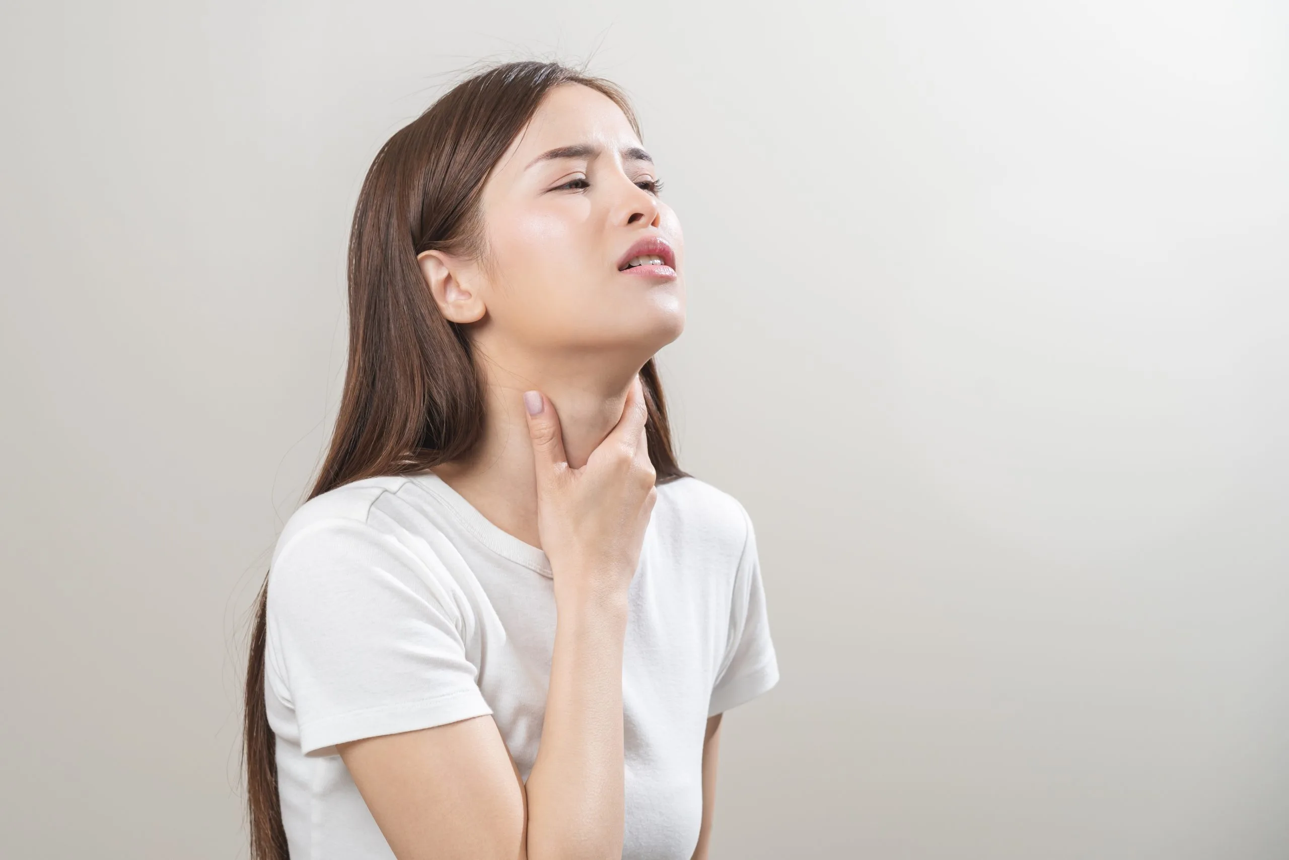 Woman touching her neck with a concerned expression, illustrating thyroid-related discomfort