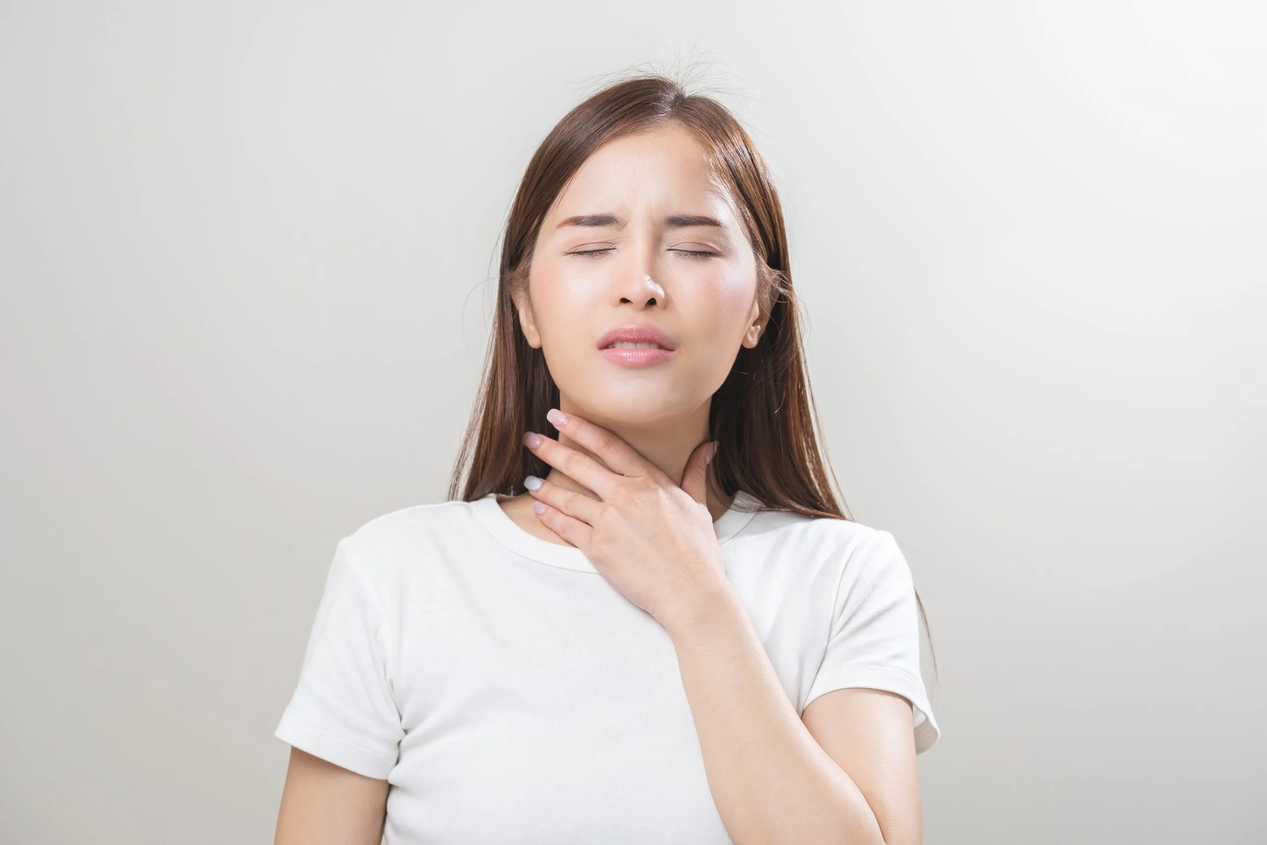 Woman touching her neck with a painful expression