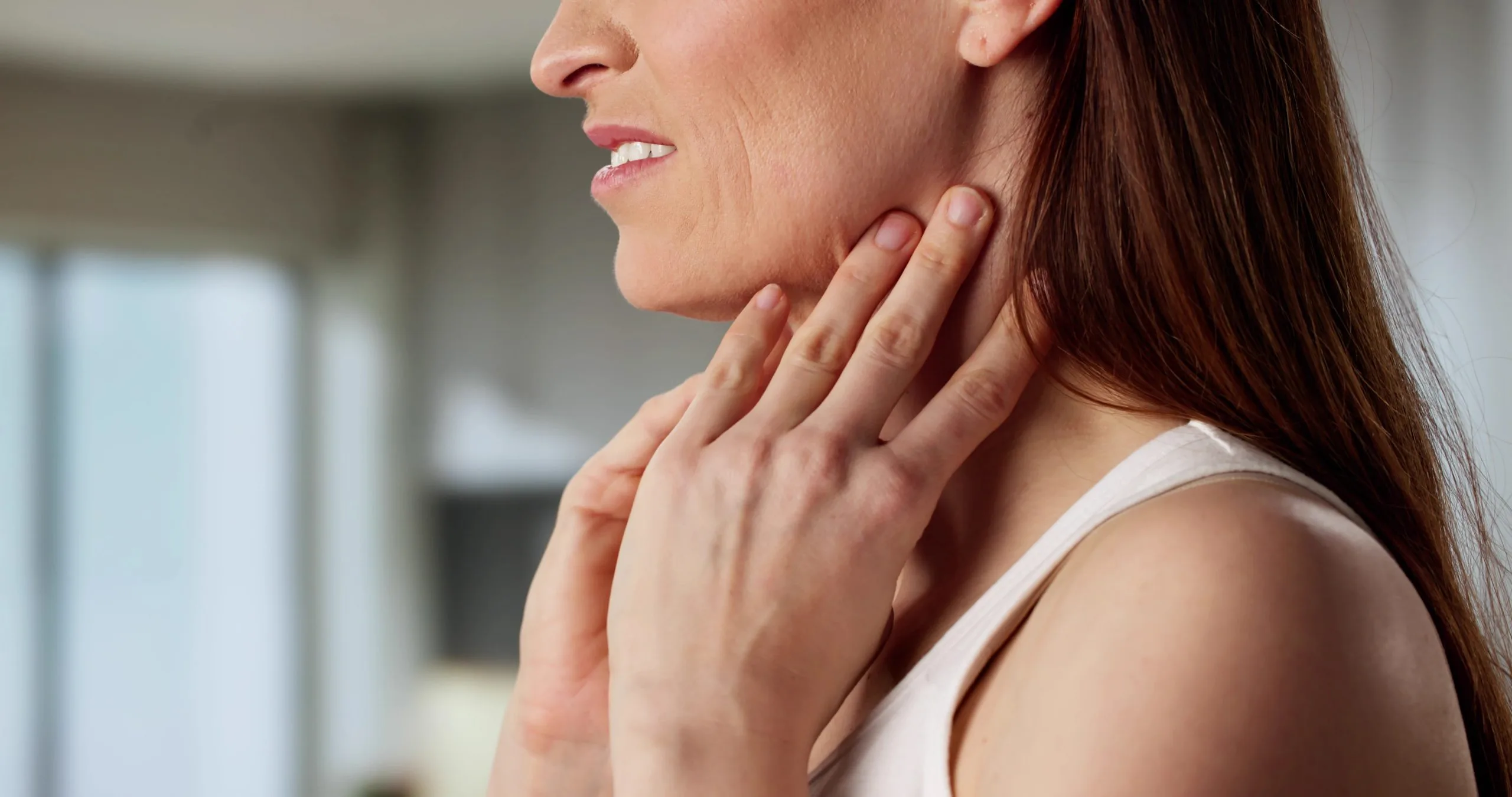 Woman holding her neck, illustrating thyroid gland discomfort
