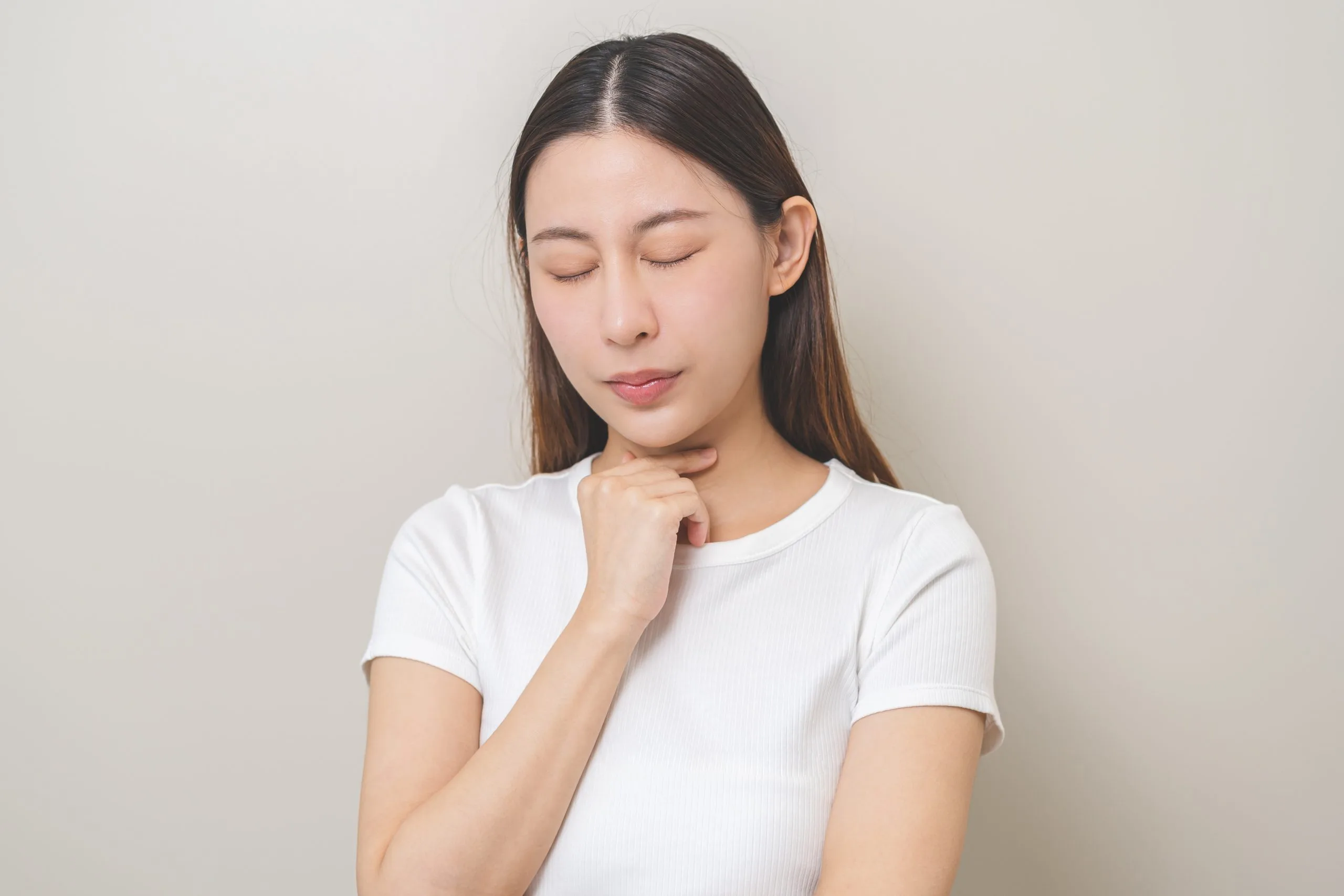 Woman touching her neck, illustrating thyroid discomfort or swelling