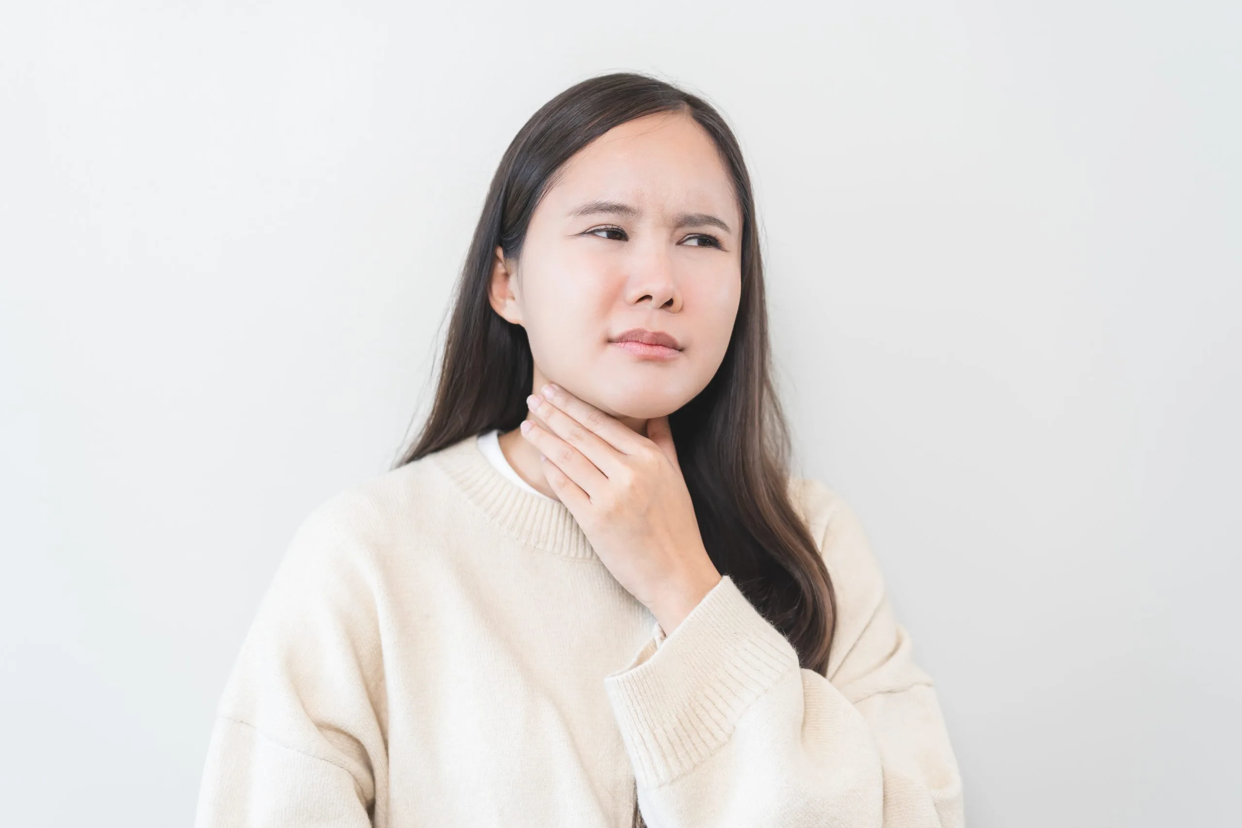 Woman holding her neck with an uncomfortable expression, illustrating thyroid discomfort
