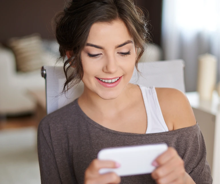 Woman smiling while viewing appointment confirmation on mobile phone