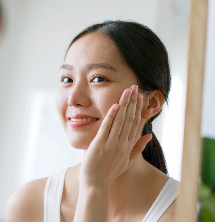 Woman touching her cheek and smiling at camera in bright room