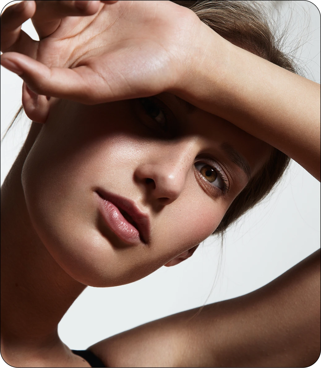 Woman with hand to forehead, skin glowing under natural light