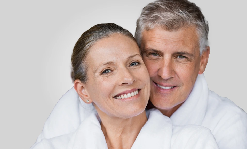 Middle-aged couple smiling together against neutral background