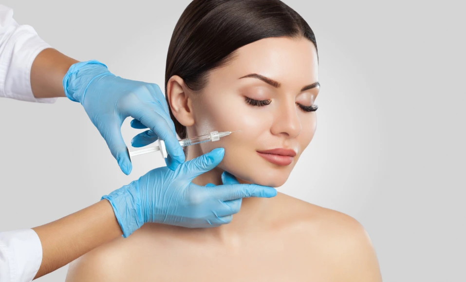 Gloved hands administering injection to woman's cheek during cosmetic treatment