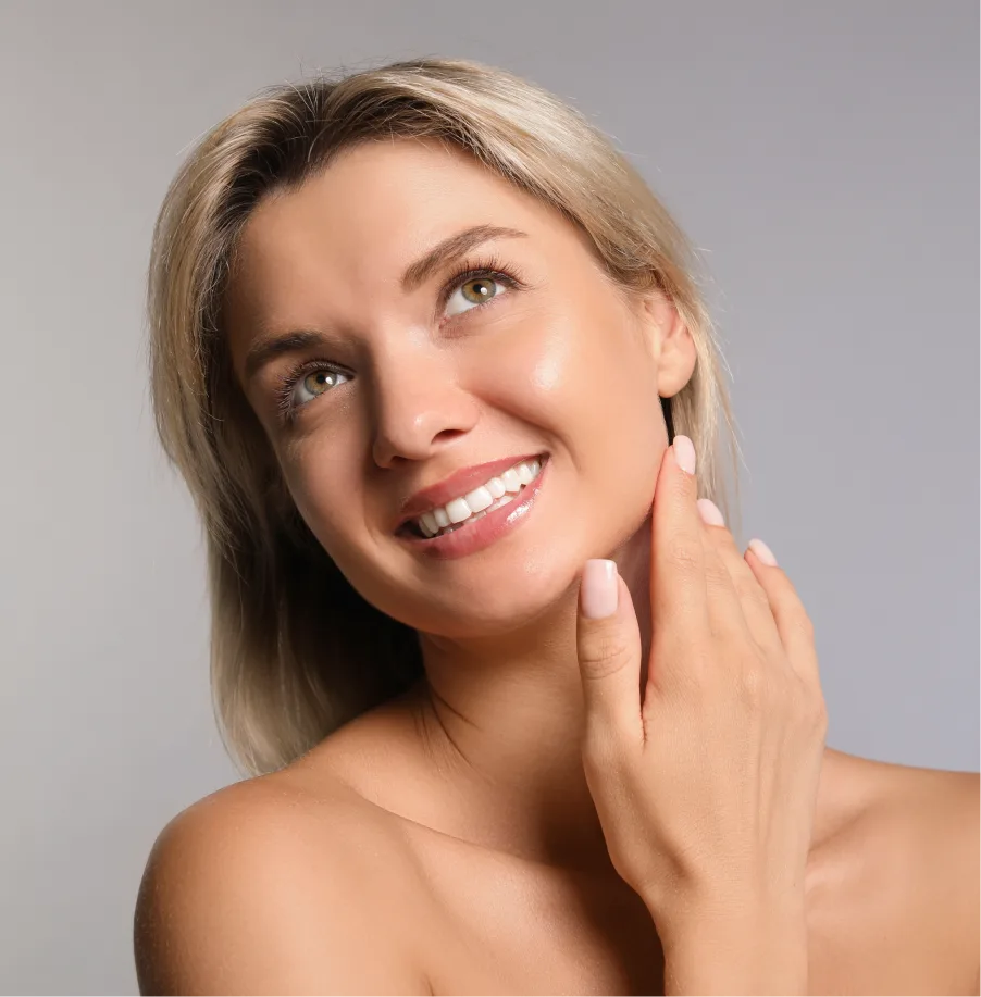 Woman touching her cheek and smiling, demonstrating smooth, glowing skin