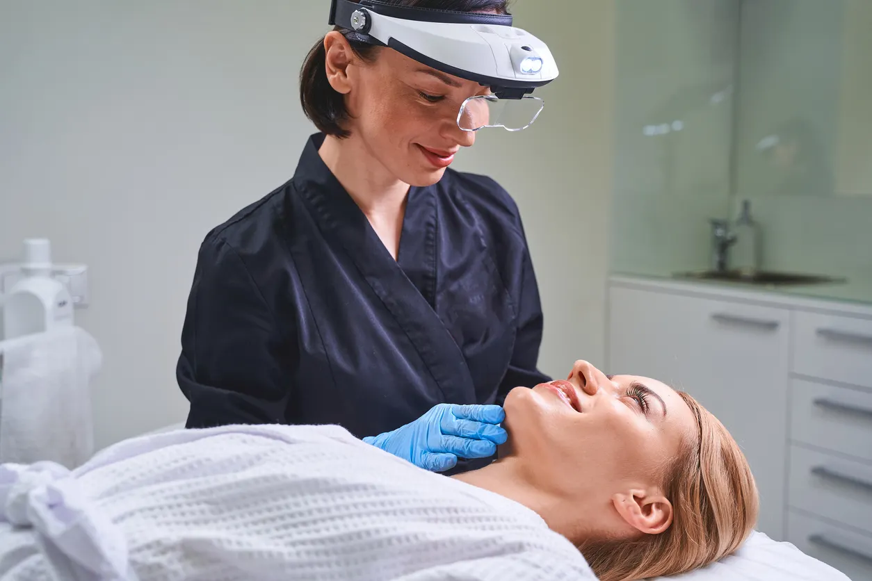 Practitioner wearing headpiece magnification device examining a patient's face during Morpheus8 consultation