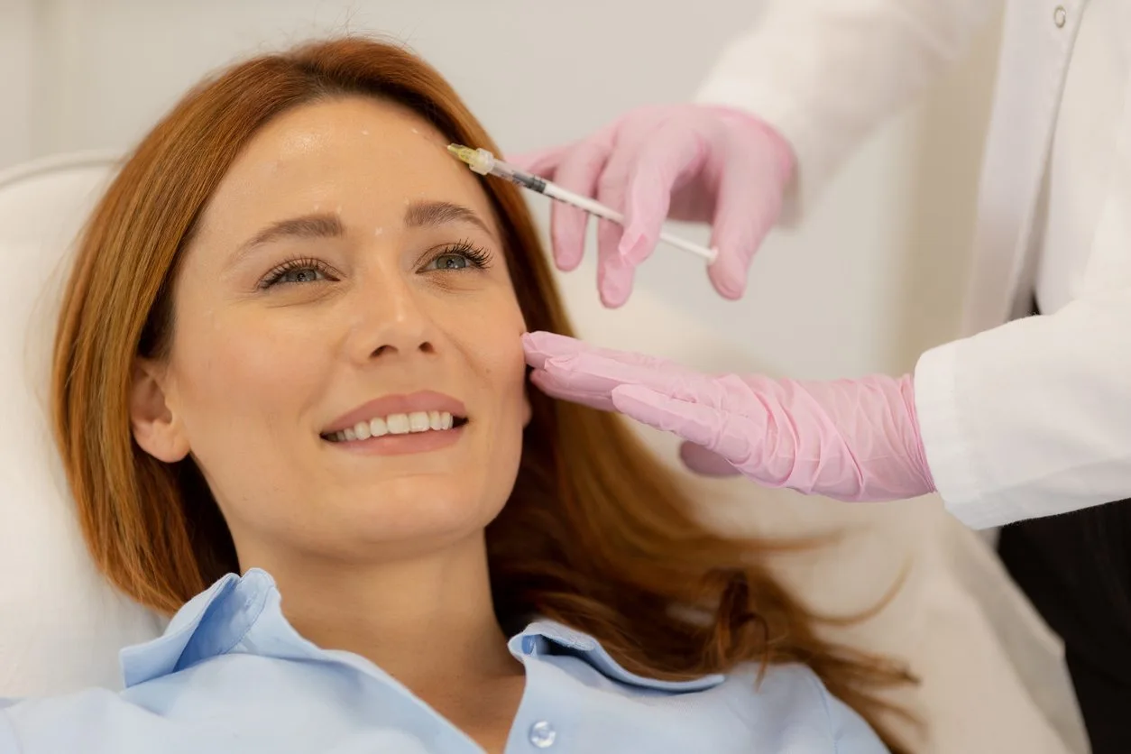 Provider in pink gloves administering Botox injection to patient's forehead