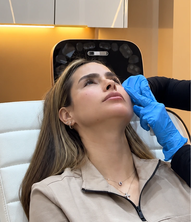 Provider in blue gloves assessing a patient's facial structure during an injectables consultation
