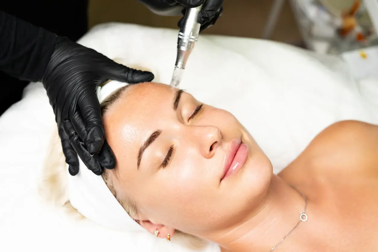 Provider in black gloves performing a facial treatment on a relaxed patient with a handheld device