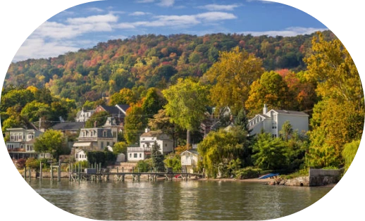 Waterfront view of Nyack, NY with residential homes, trees in fall colors, and river in foreground