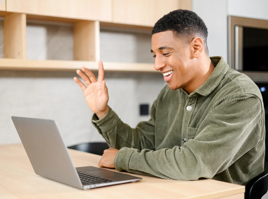Young man waving as he joins a secure video visit from home
