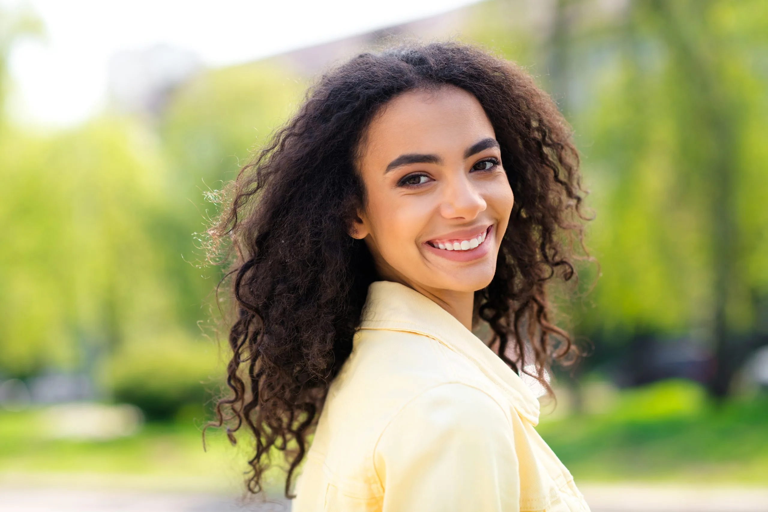 Smiling young woman outdoors, feeling calm after PTSD and trauma treatment