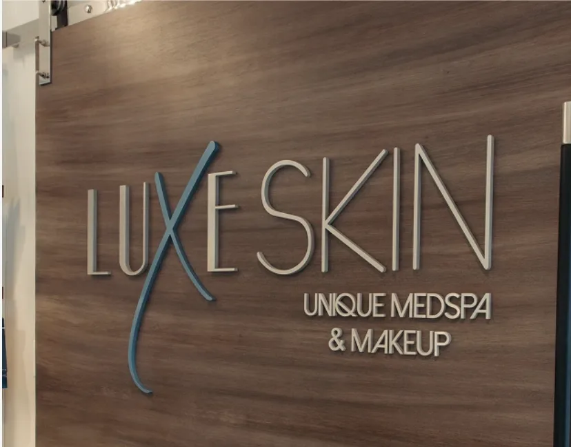 Luxe Skin Unique Medspa & Makeup illuminated wood sign on clinic wall