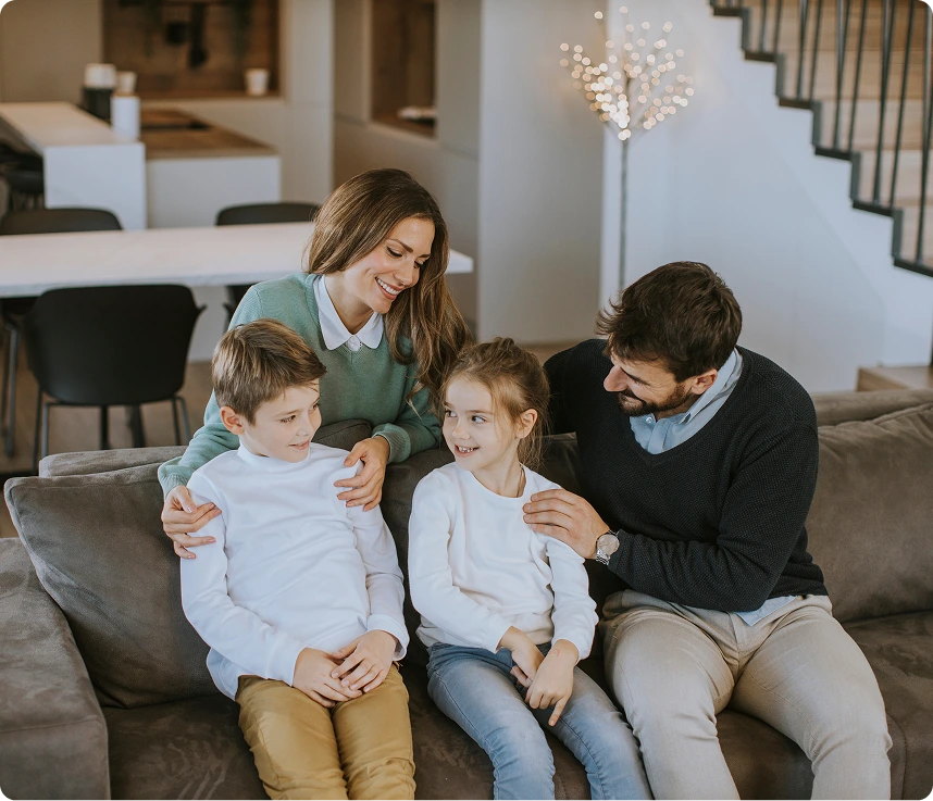 Family of four sitting together on a gray couch in a modern home interior