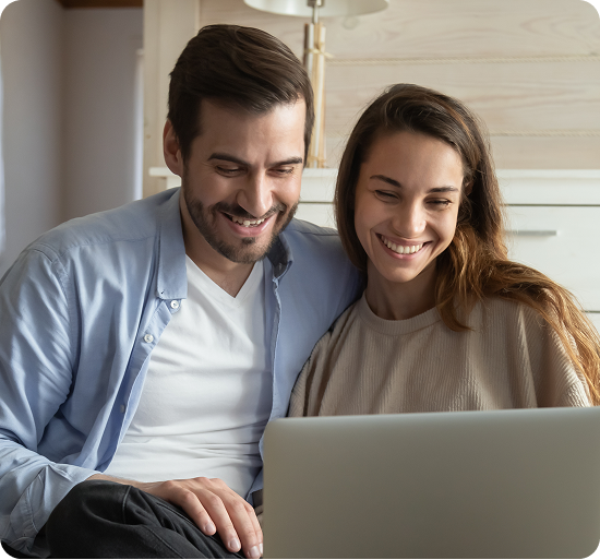 Man and woman smiling while looking at laptop together indoors