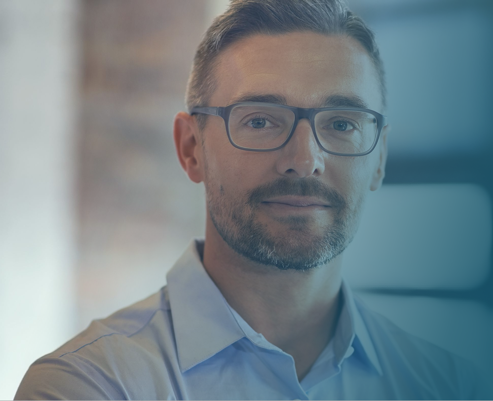 Man wearing glasses and light blue shirt in professional setting