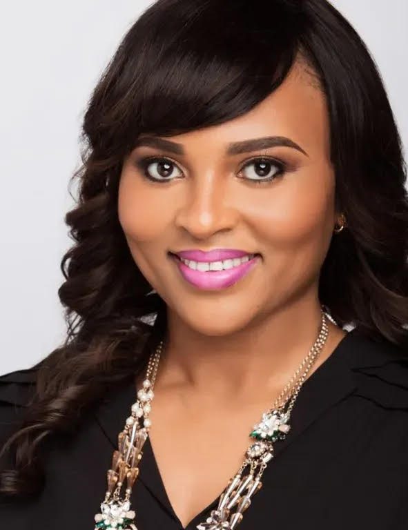 Faith Ogala, professional headshot wearing black blazer with decorative necklace, smiling against light background