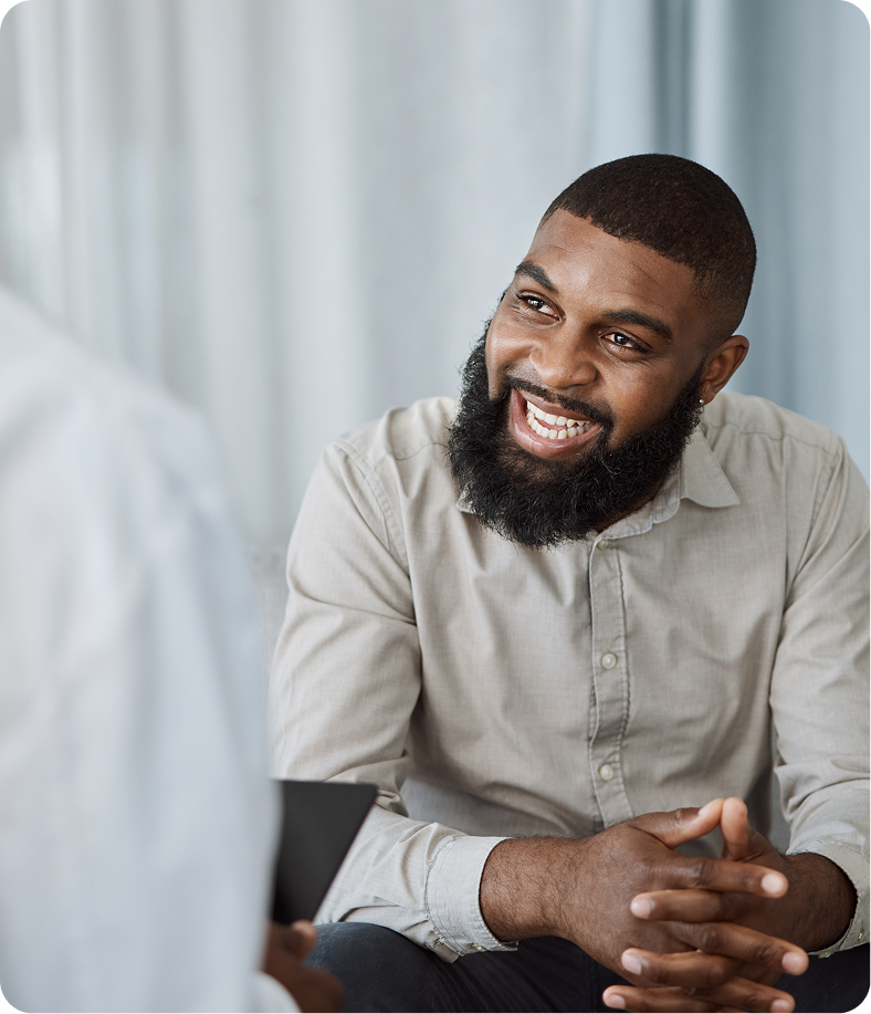 Man in beige shirt smiling during psychiatric assessment conversation