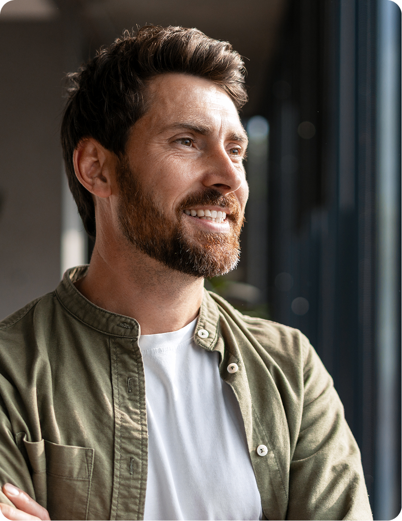 Man with beard smiling, wearing olive button-up shirt over white t-shirt