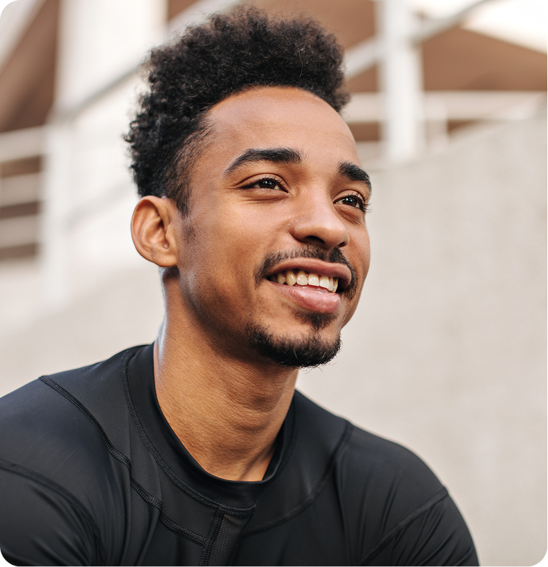 Smiling man with dark hair and facial hair wearing black t-shirt against light background
