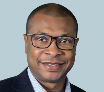 Man wearing glasses and light blue striped shirt smiling at camera against light blue background
