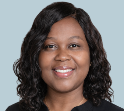 Woman with curly black hair smiling at camera wearing black top against light blue background