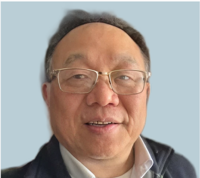 Man wearing glasses and dark jacket smiling against light blue background