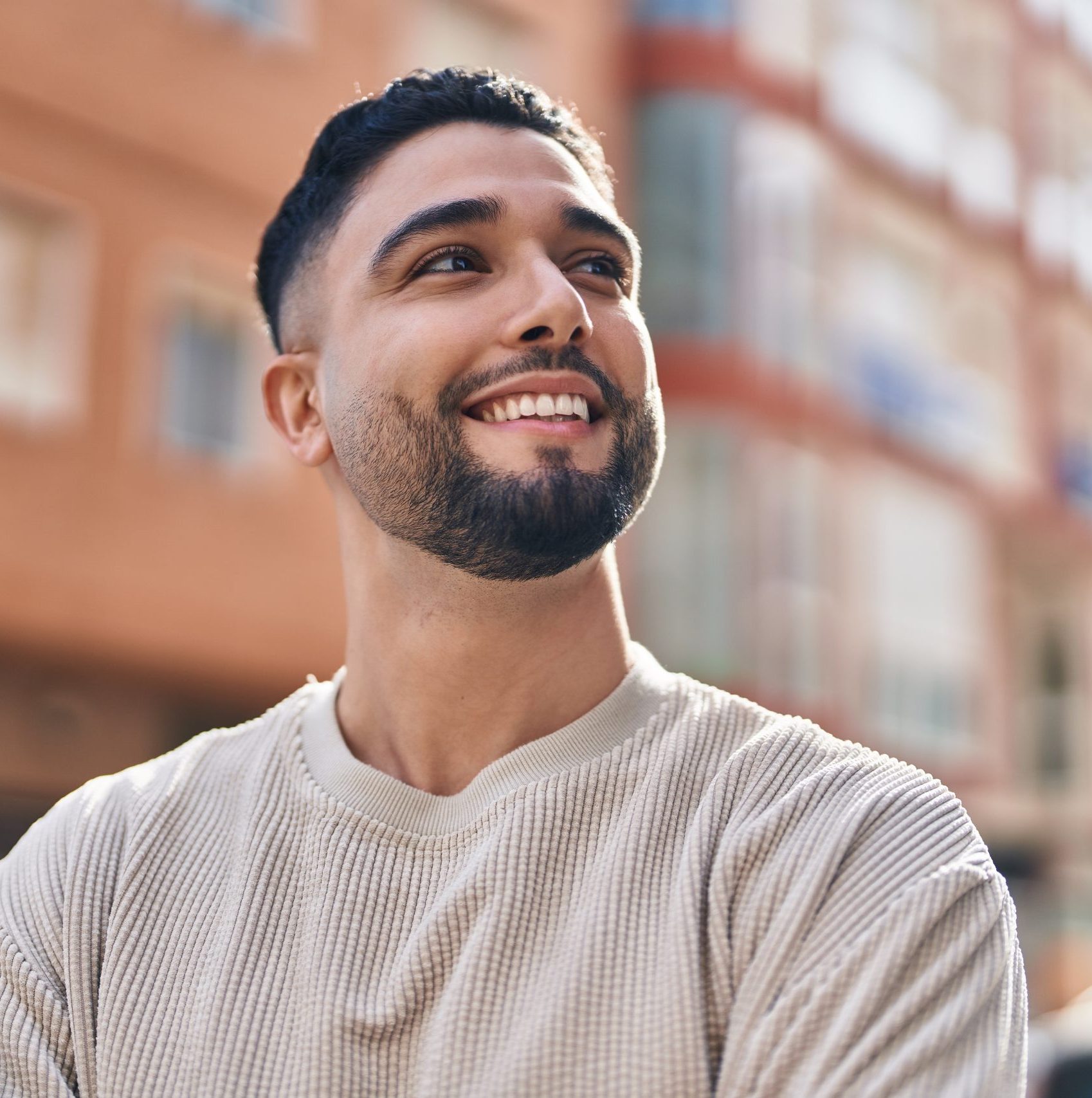 Man smiling outdoors in front of blurred brick building