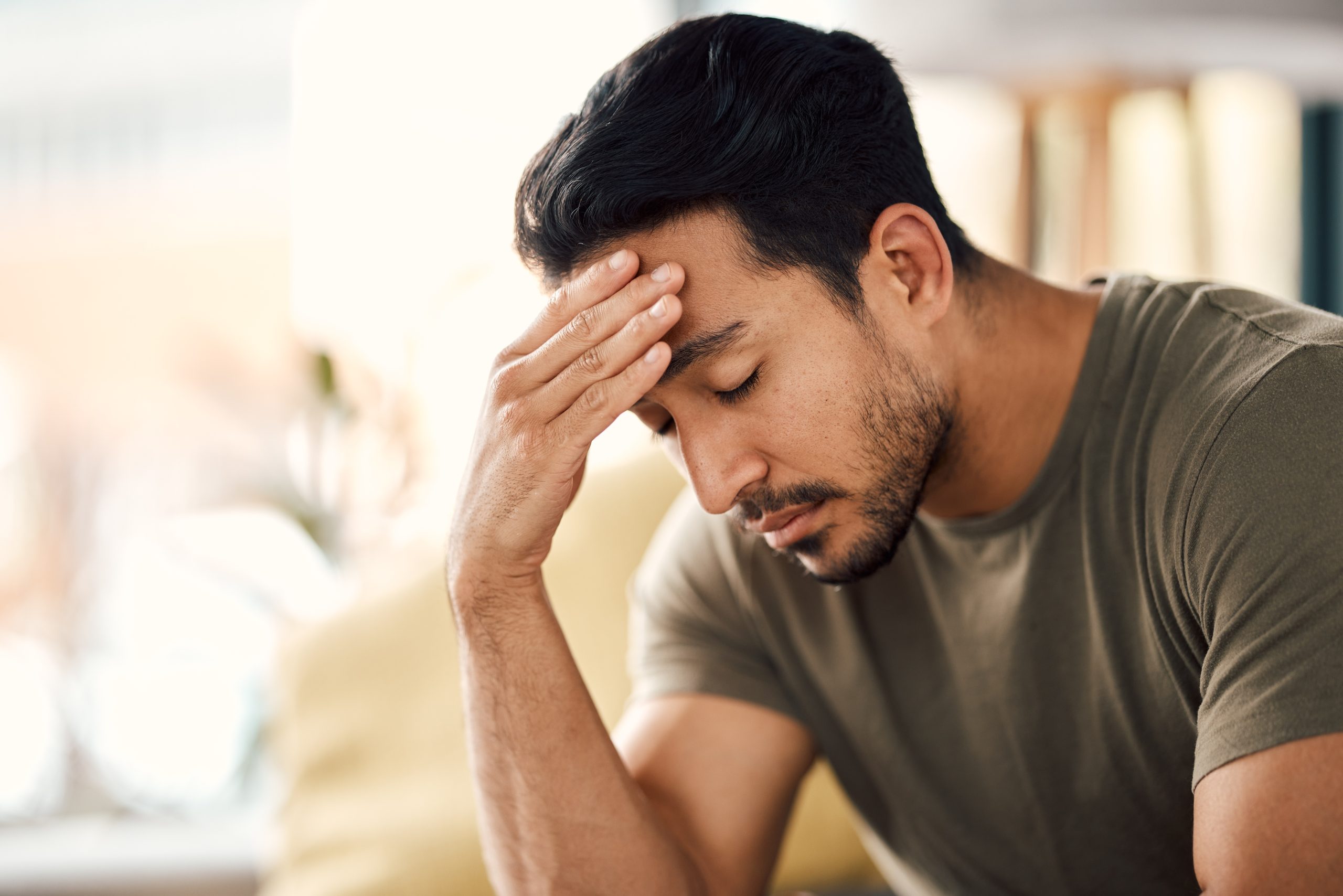Man holding his head with hand, eyes closed, experiencing headache or stress