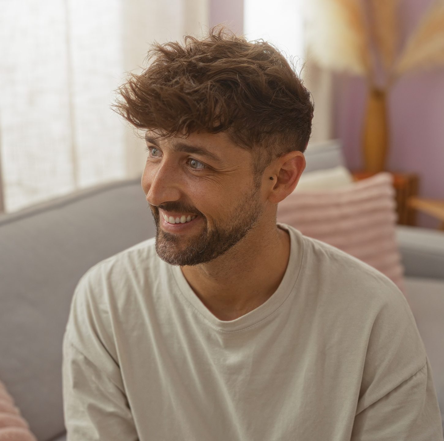 Man with brown hair and beard smiling in a modern interior space