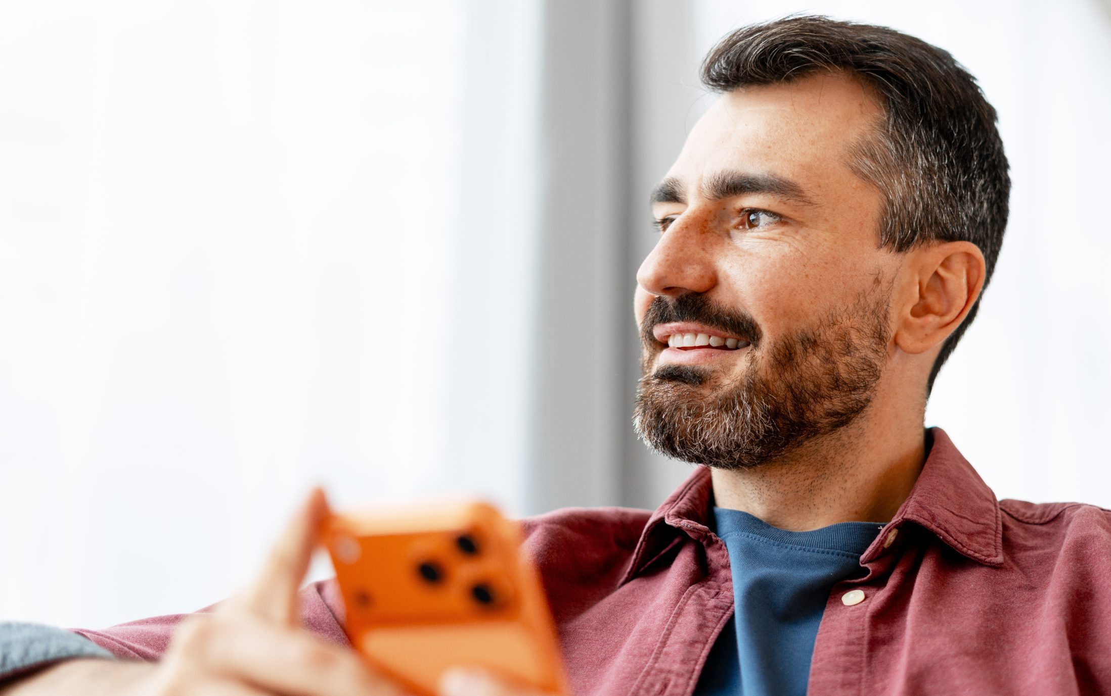Man with beard smiling while holding orange toy, looking upward