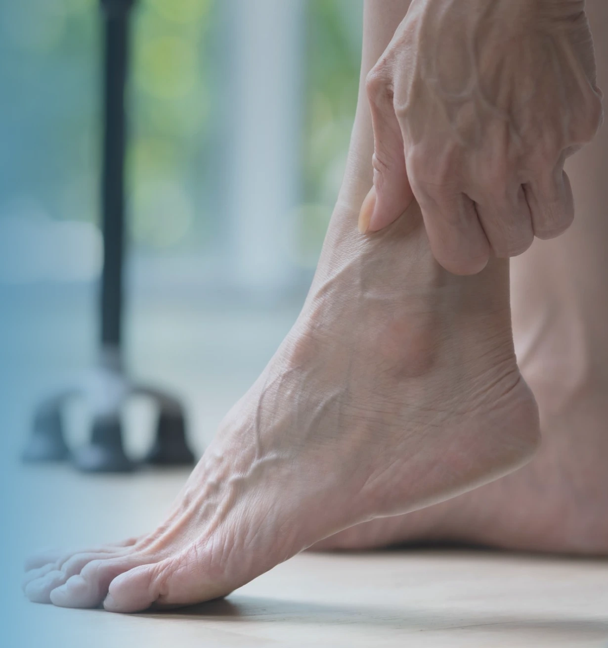 Person holding their lower leg and ankle, demonstrating foot discomfort