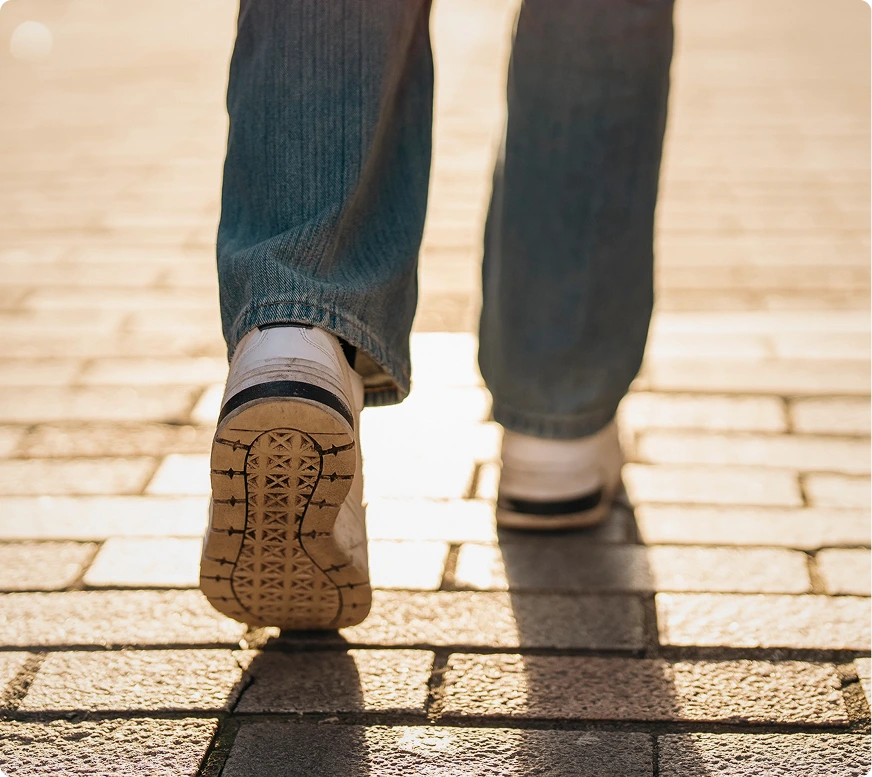 Person walking on a brick path, showing the sole of a brown laced shoe