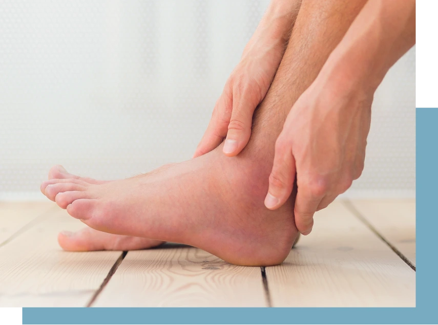 Hands examining a swollen ankle on a person sitting on a wooden floor