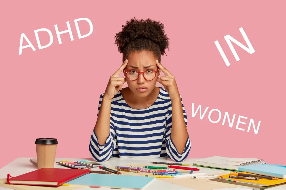 Woman wearing glasses and striped shirt at desk with school supplies, text reading ADHD IN WOMEN