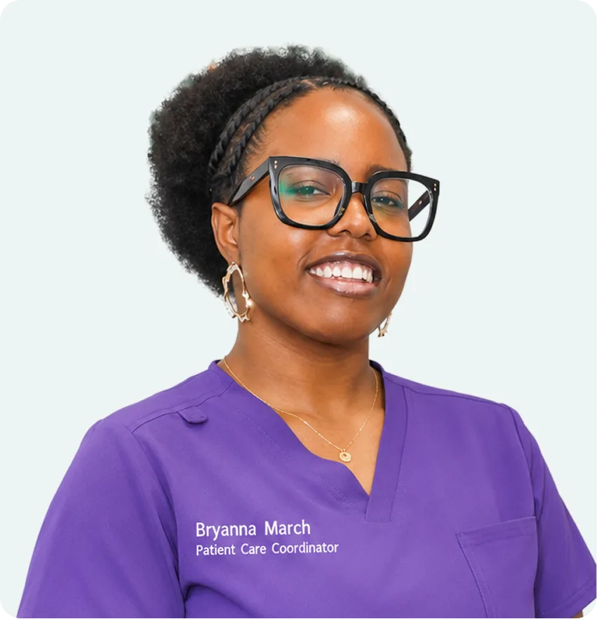 Bryanna March, Patient Care Coordinator, wearing purple scrubs and glasses, smiling at camera