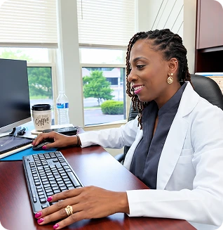 Tai Ajani, DNP, PMHNP-BC, at her desk in the Laurel office reviewing patient information on her computer
