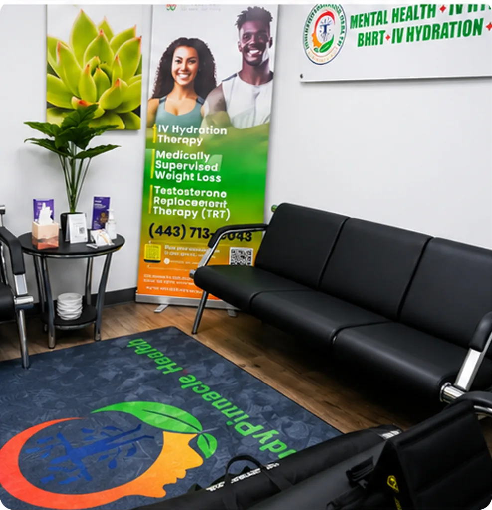Waiting room with black sofa, plant, IV hydration therapy banner featuring two smiling patients, and branded floor mat