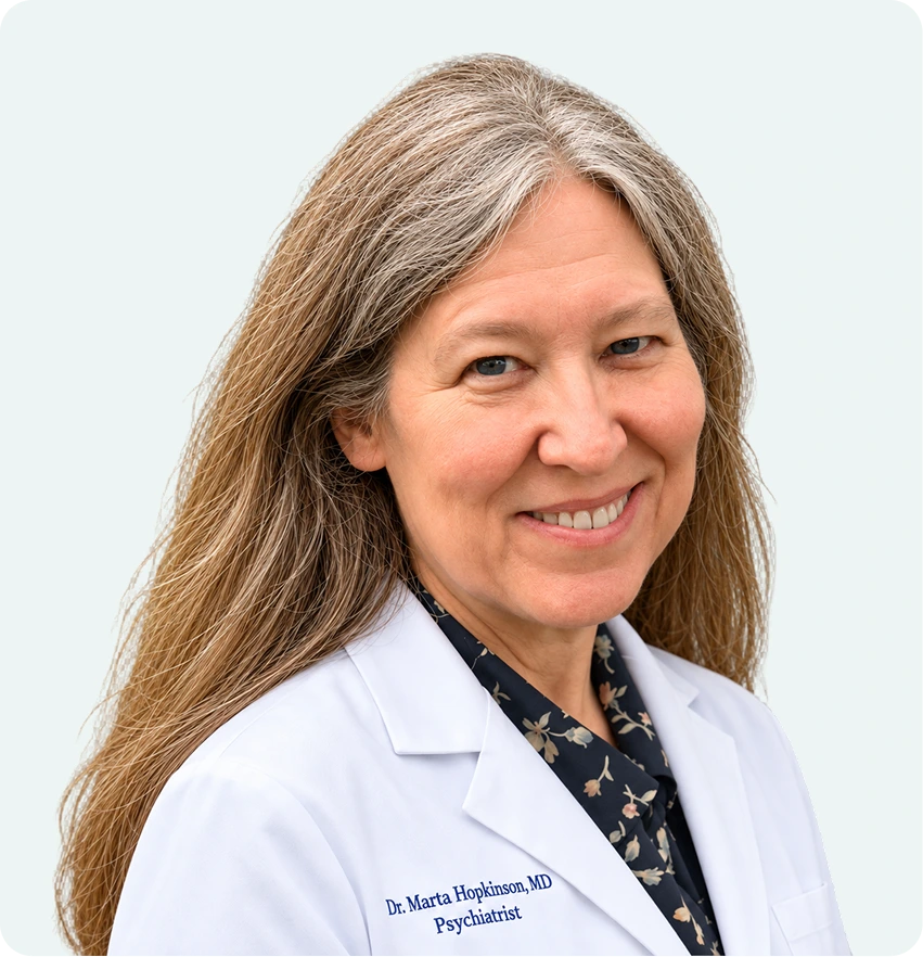 Dr. Marta Hopkinson, MD, Psychiatrist, smiling in white coat against light background