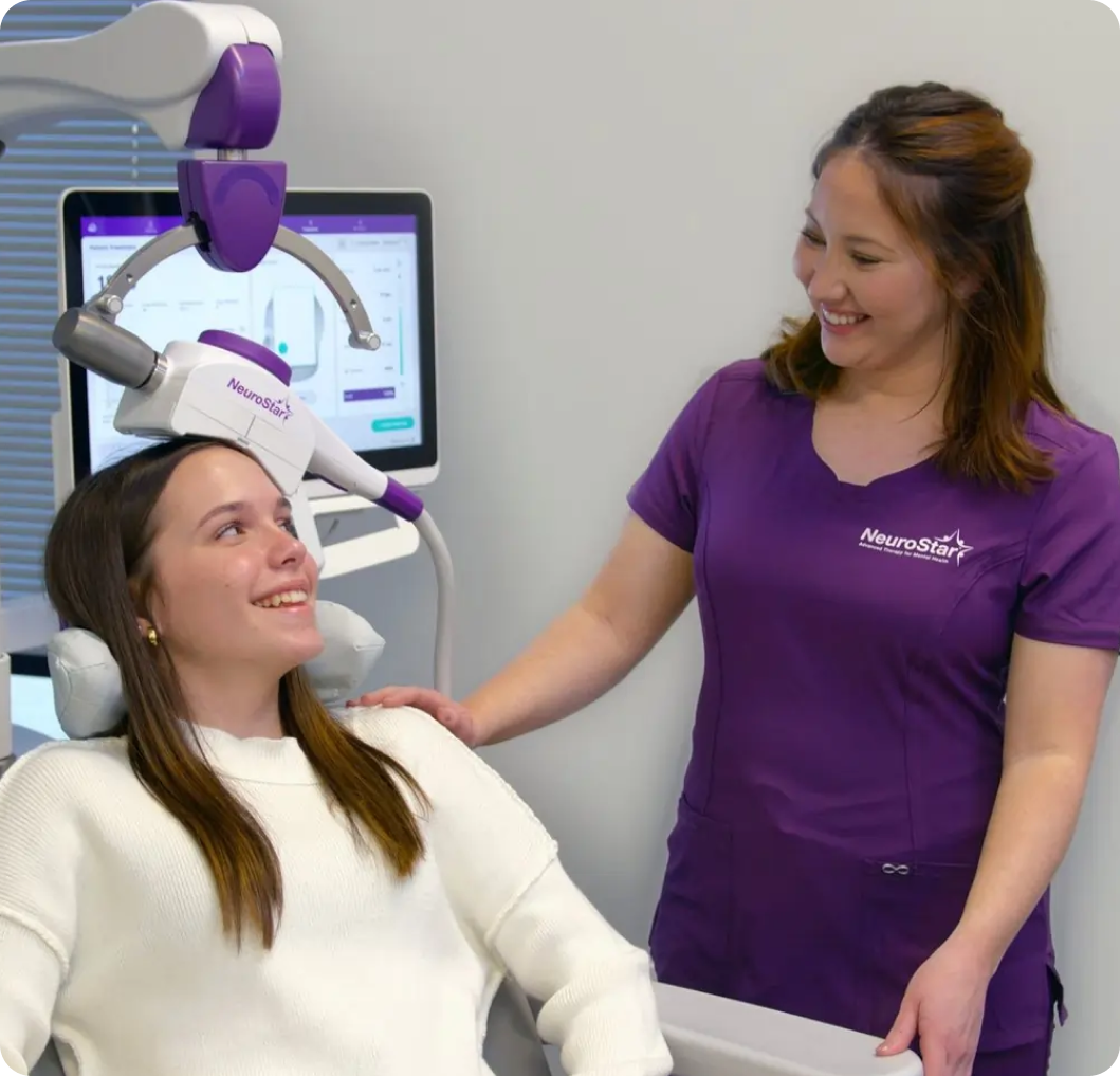 NeuroStart practitioner in purple shirt assisting patient in dental chair with purple headrest and computer display