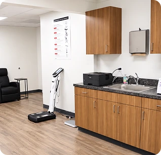 Clinical treatment room with wooden cabinetry, medical scale, and body composition analysis device at MindBodyPinnacle Health's Laurel, MD location
