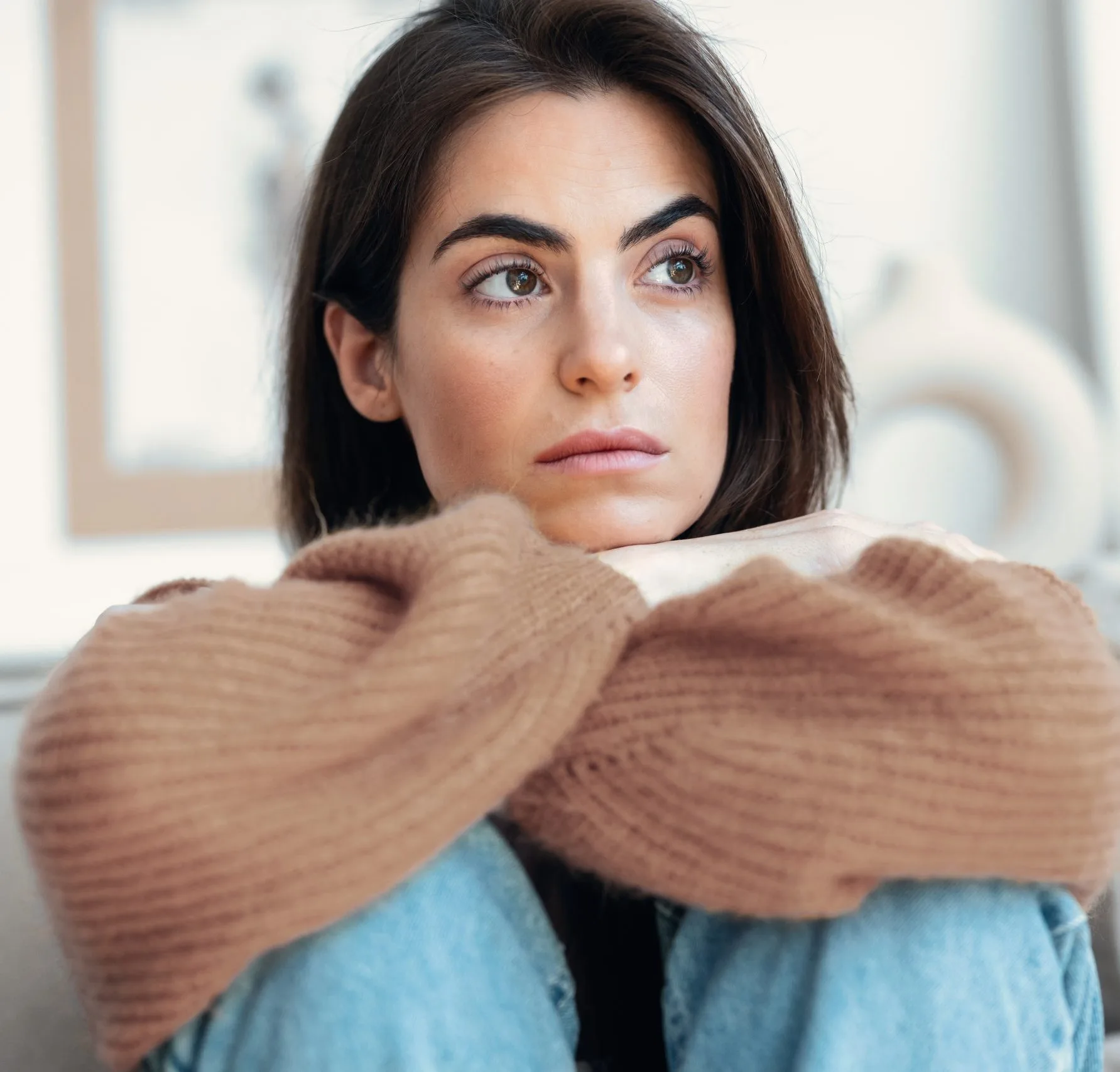 Woman with concerned expression hugging herself with arms wrapped around torso
